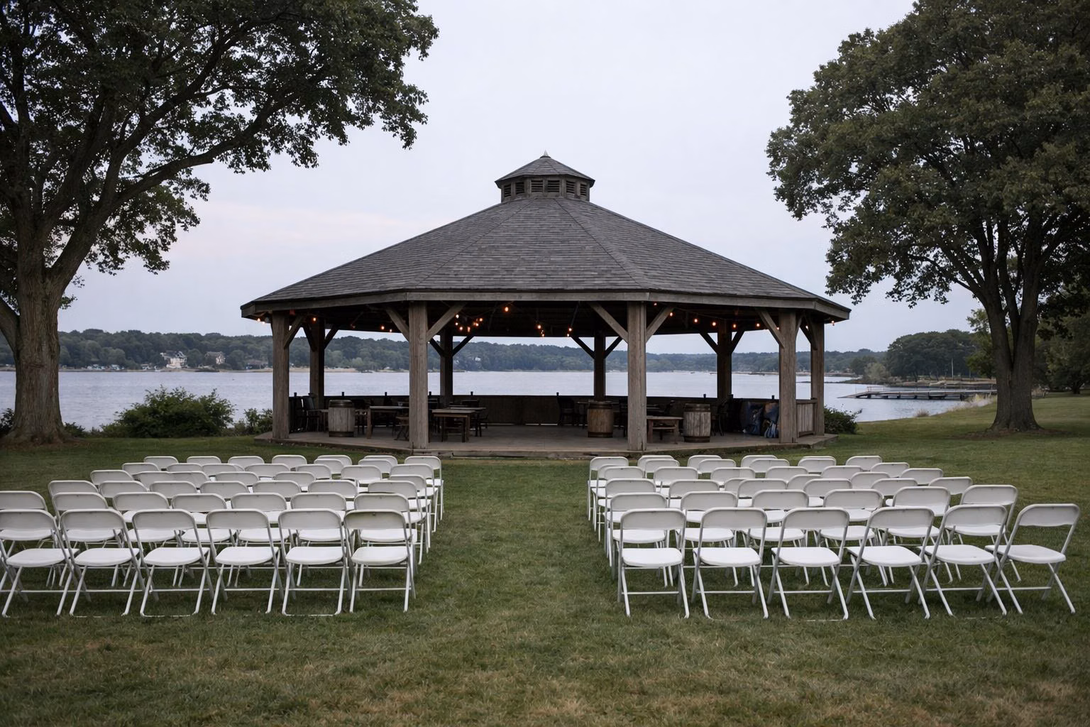 Open-sided wooden pavilion on a lawn with chairs set out