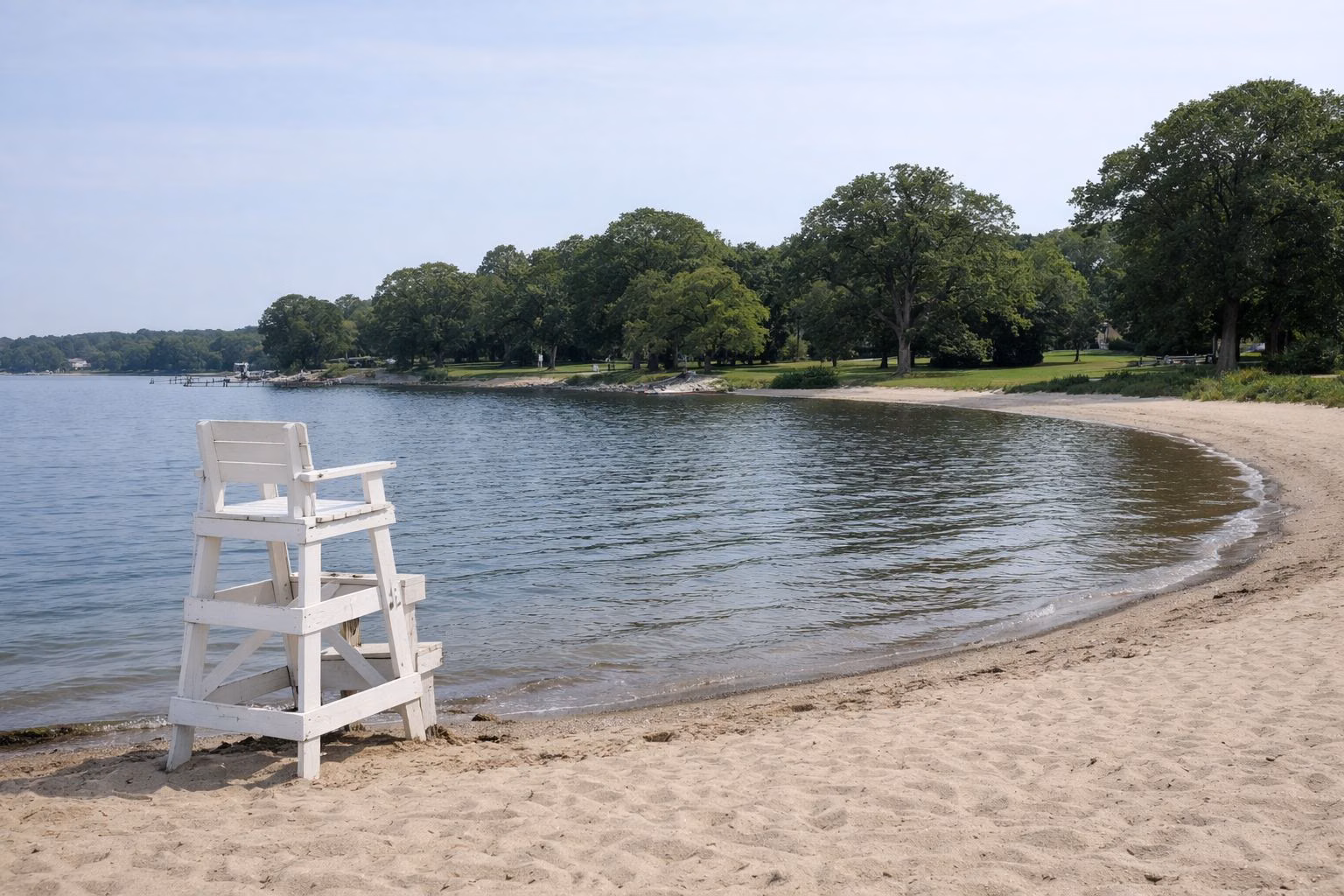 Curving sandy beach on calm bay water